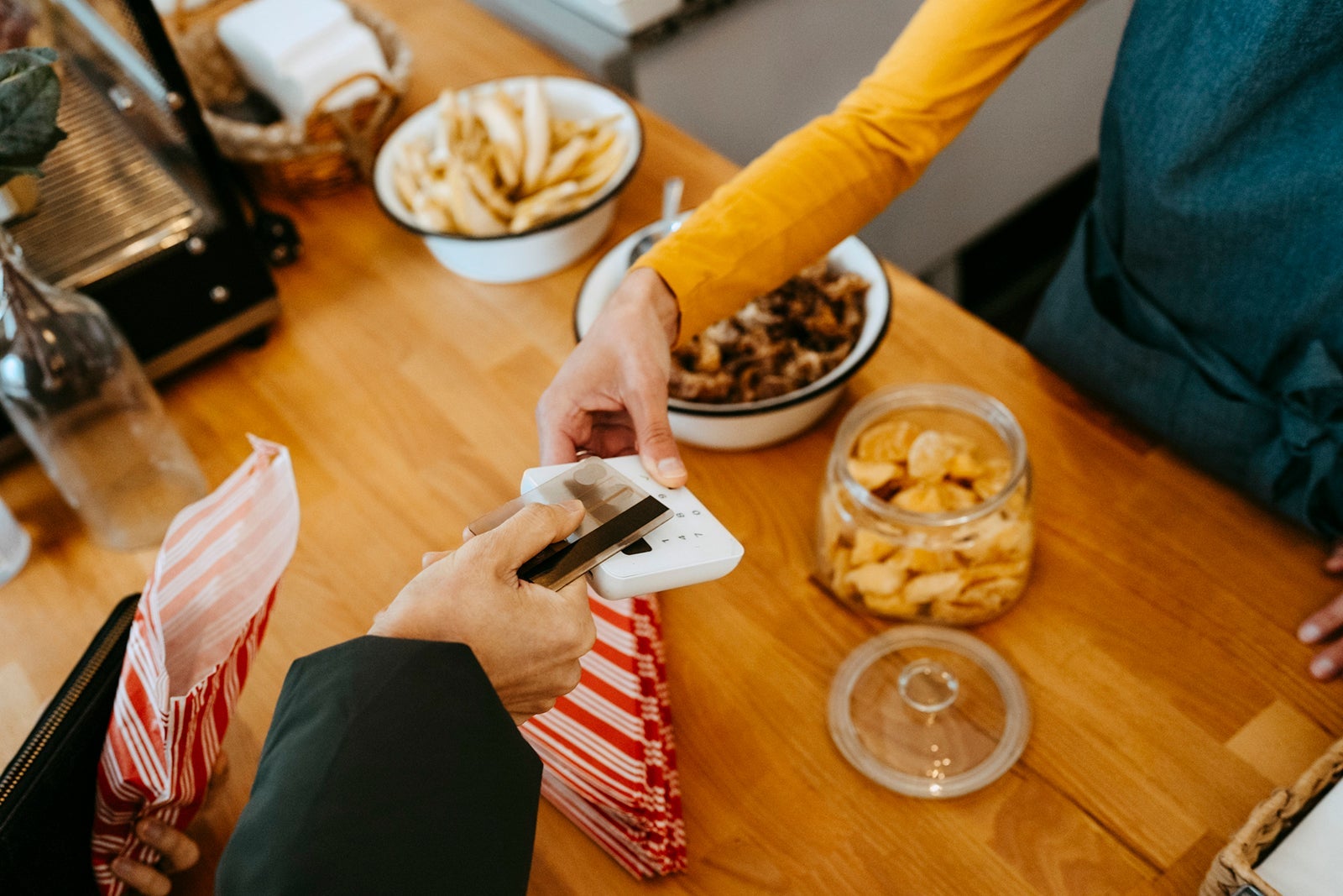 Hands of barista and customer doing tap to pay at checkout in cafe