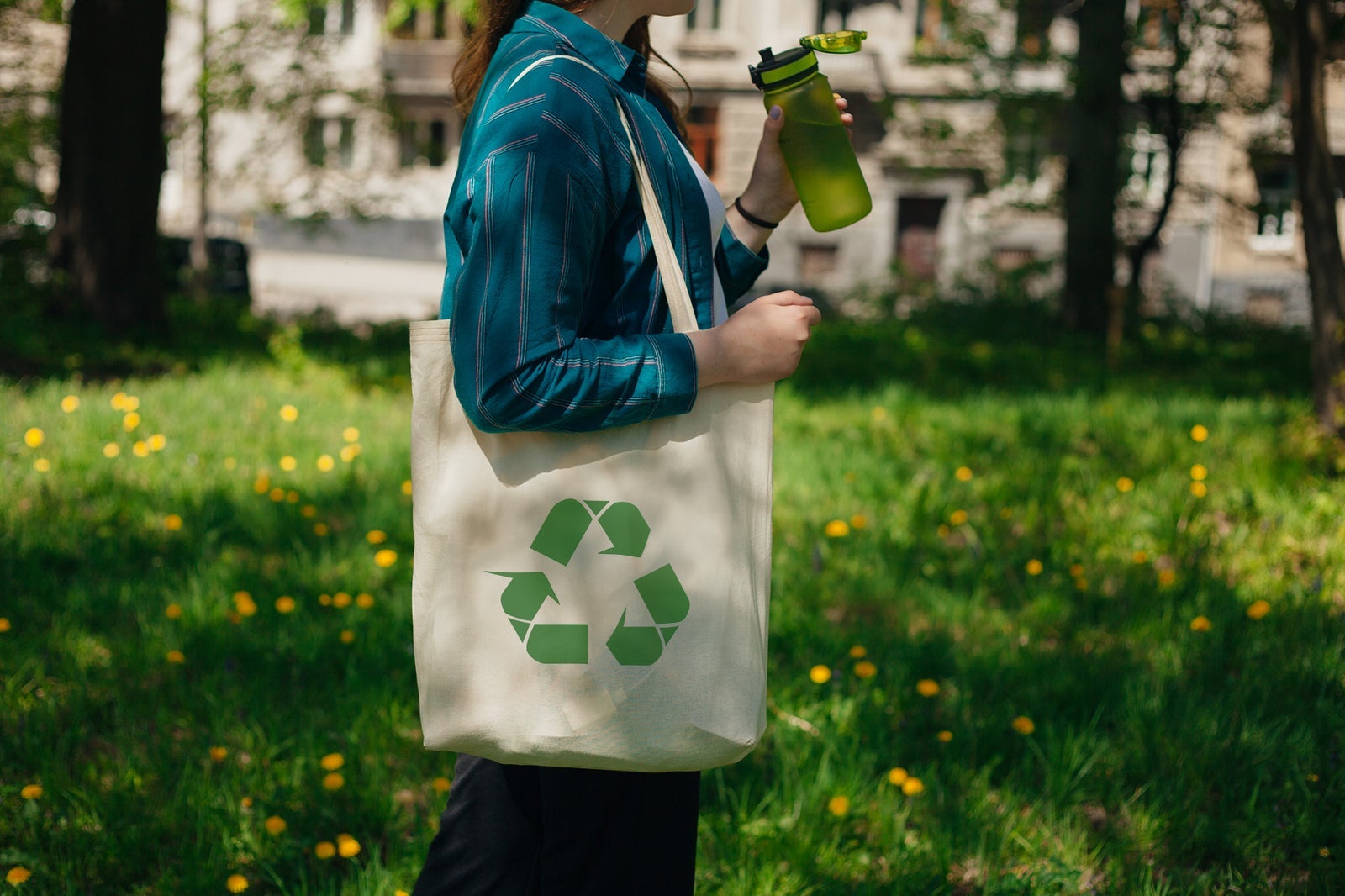 Woman holding reusable cotton zero waste bag with text No More Plastic. Outdoors portrait in sunny day. Eco friendly bags concept.