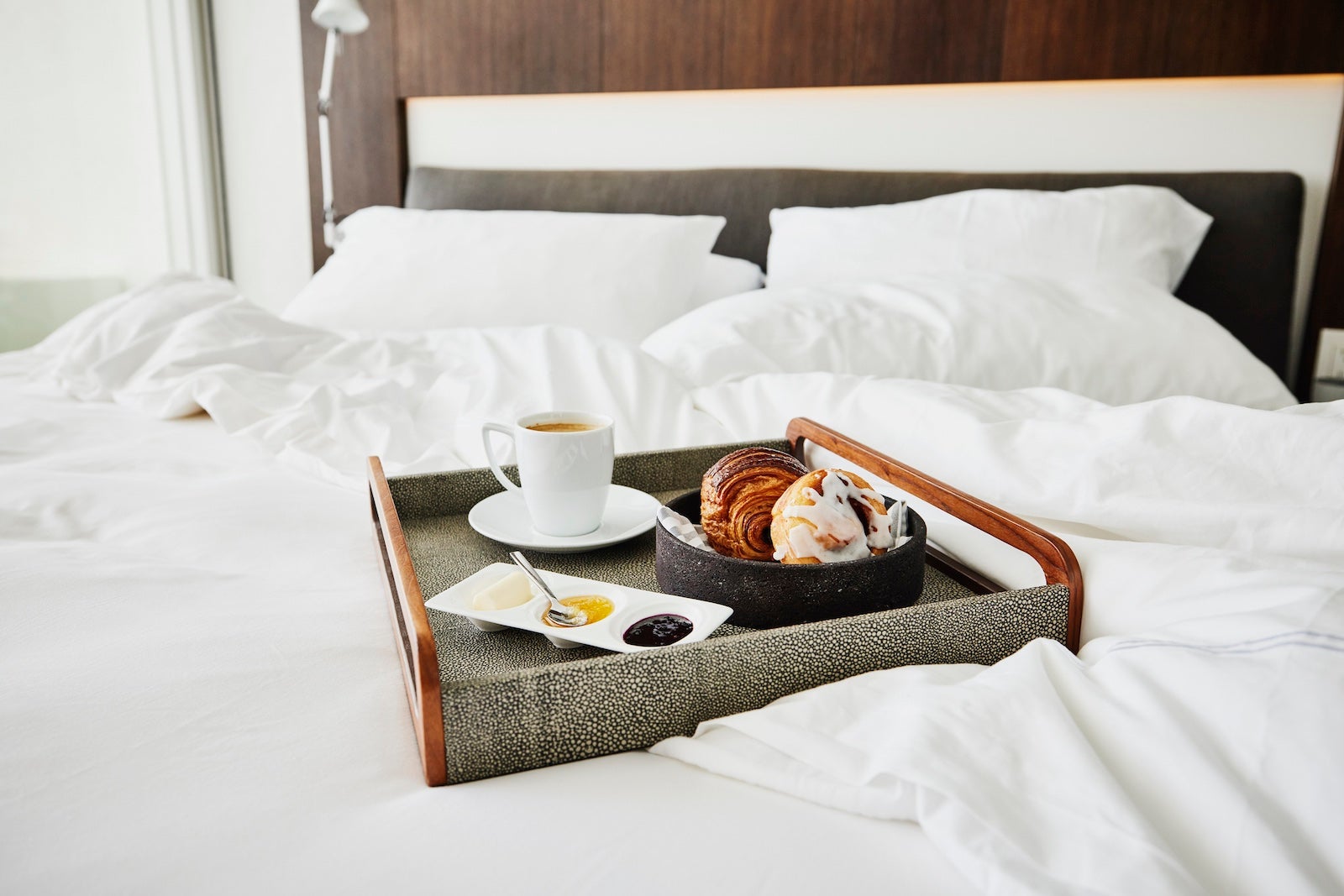 Medium shot of room service tray with breakfast on unmade bed in hotel