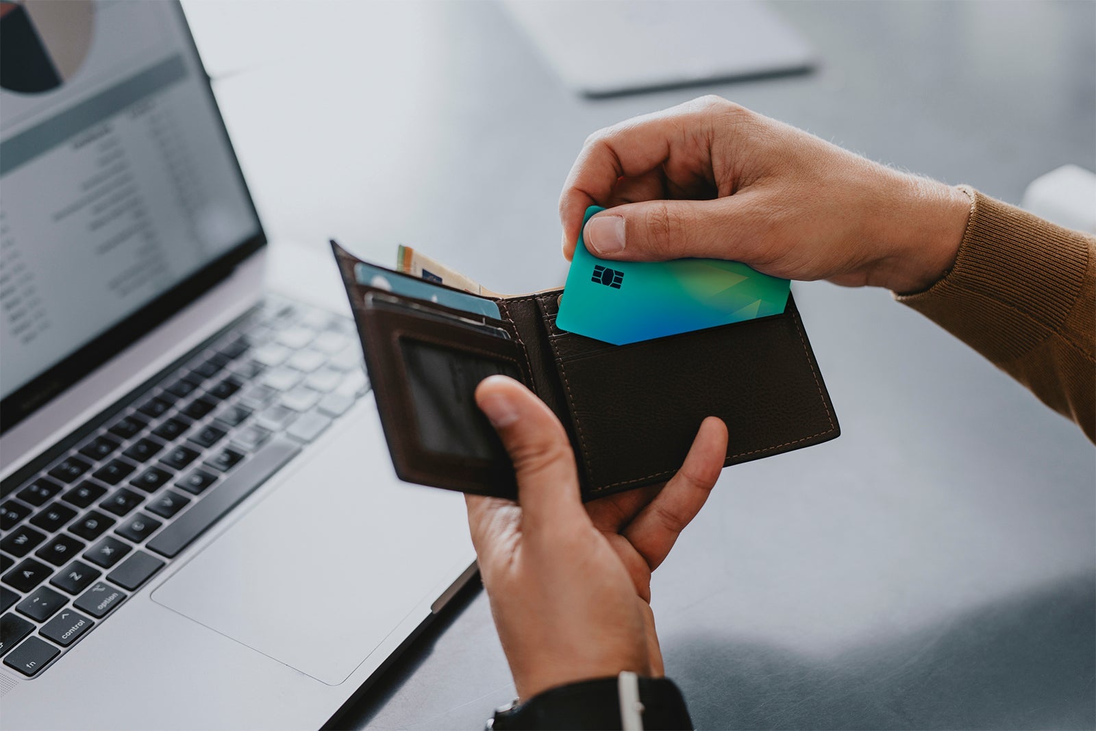 Hands of a Man Taking his Credit Card out of His Wallet to make on Online Order on his Laptop Computer