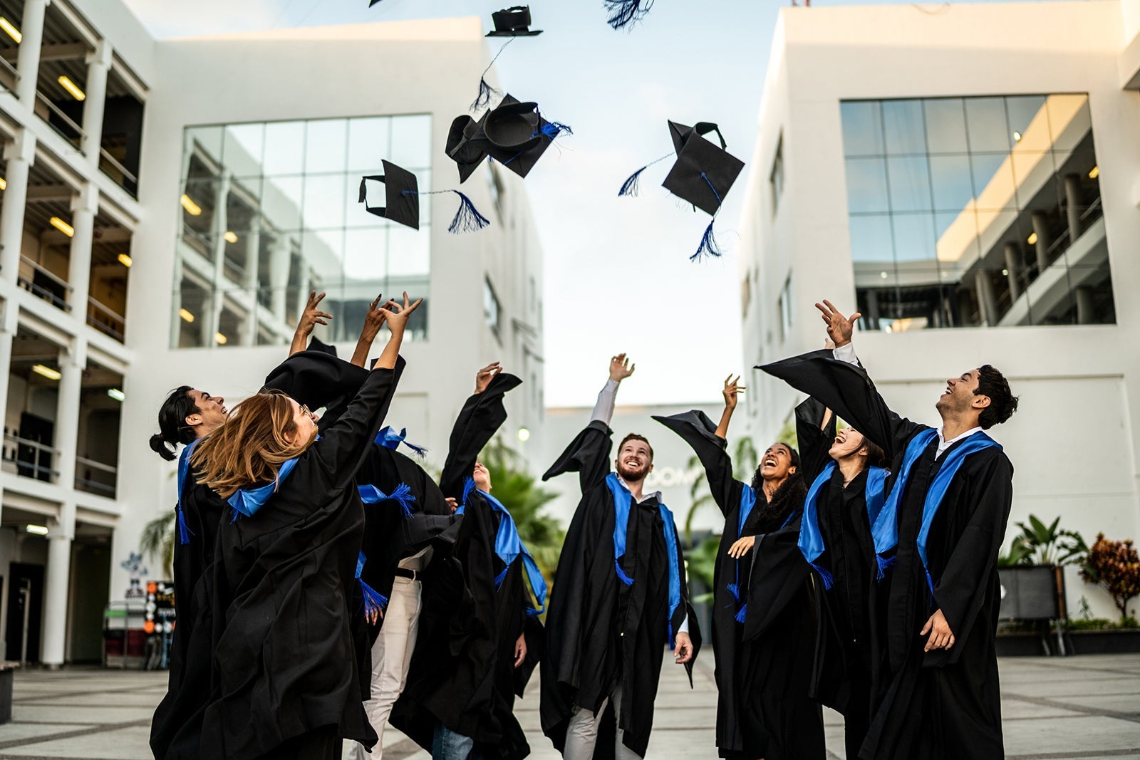 Young graduates throwing their mortarboard in the air while celebrating on graduation