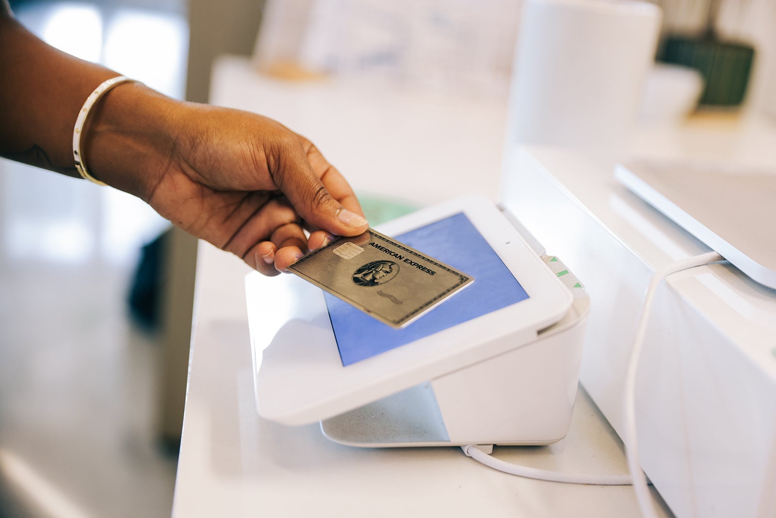 Detail of a LatinX millennial woman's hand using a credit card for payment .