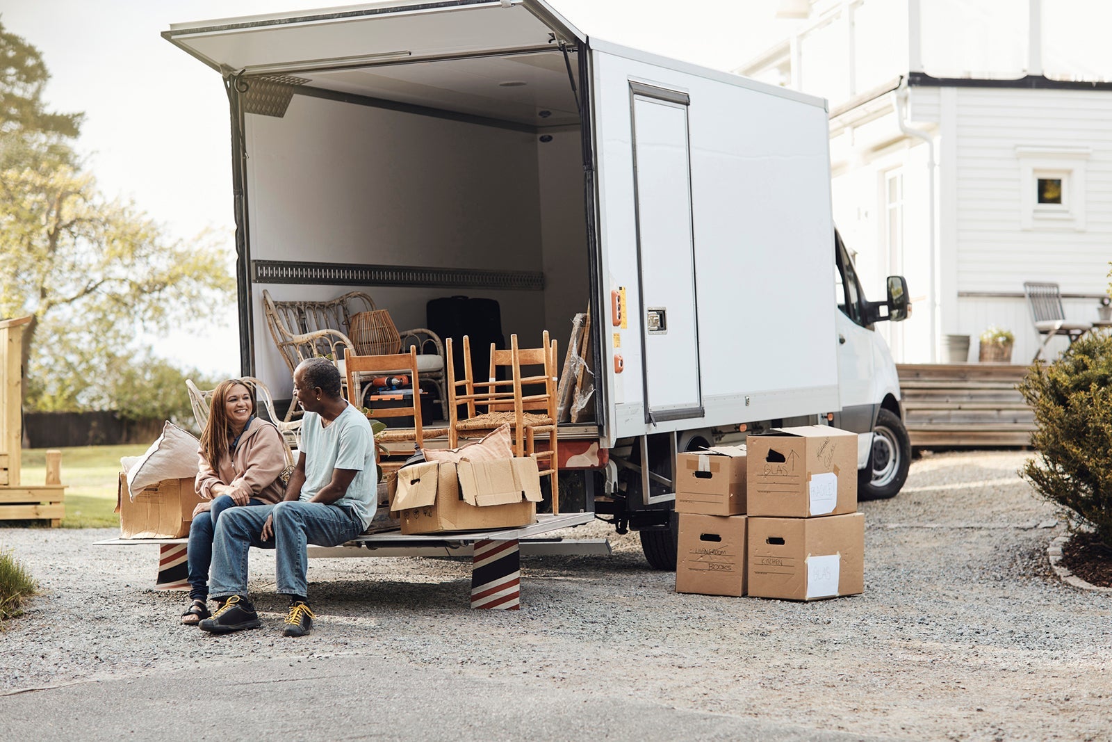Couple talking to each other while sitting by cardboard boxes near van