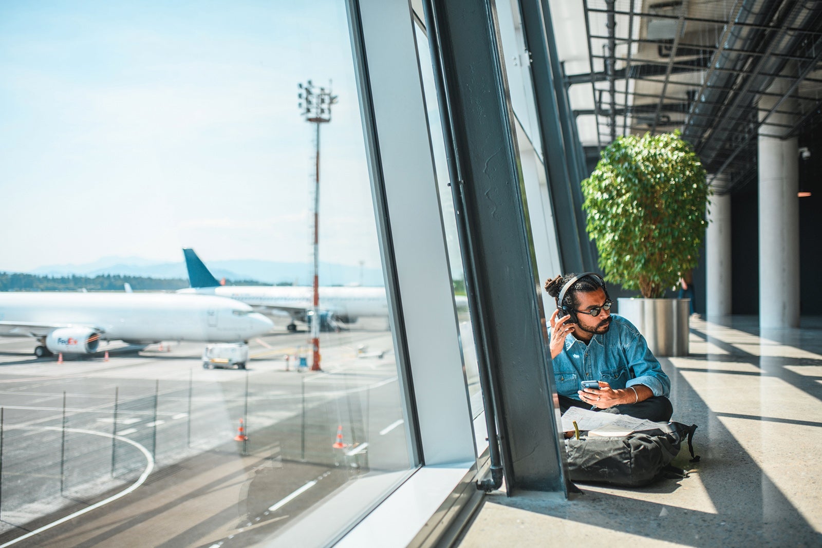 Indian Male At The Airport Using Smartphone And Listening To Music