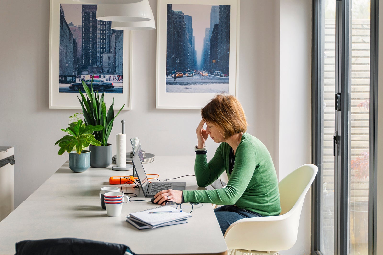 A stressed mature woman works from her dining table at home