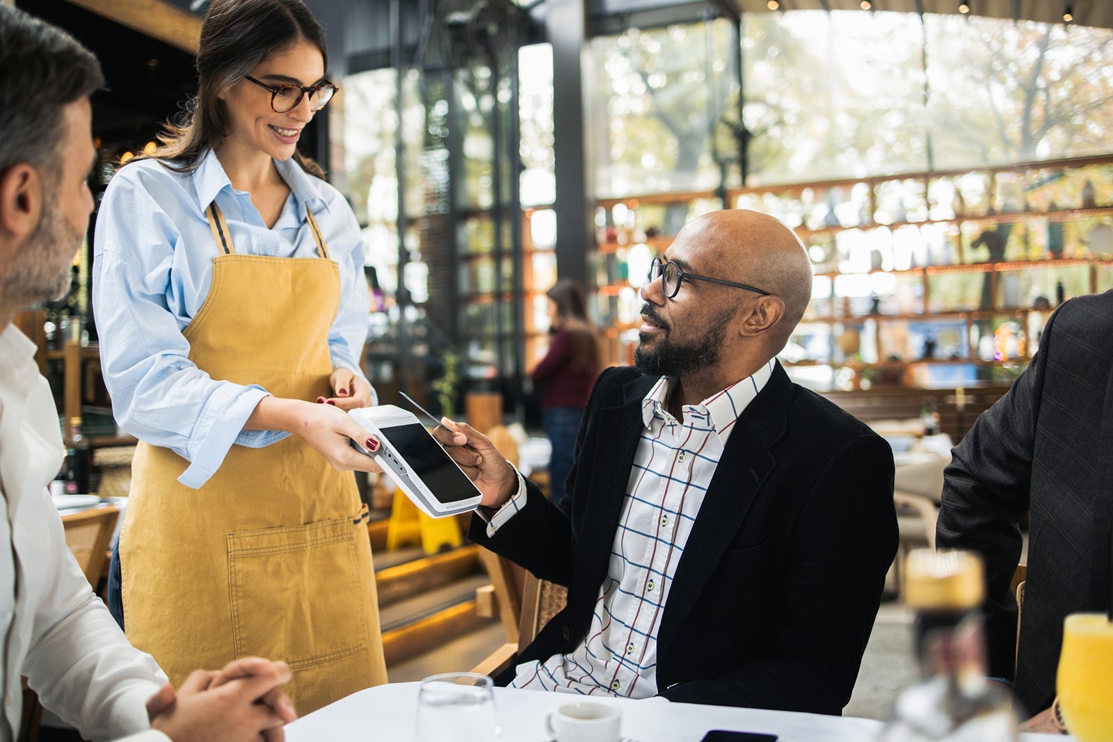 Latin American businessman making a contactless payment at the restaurant