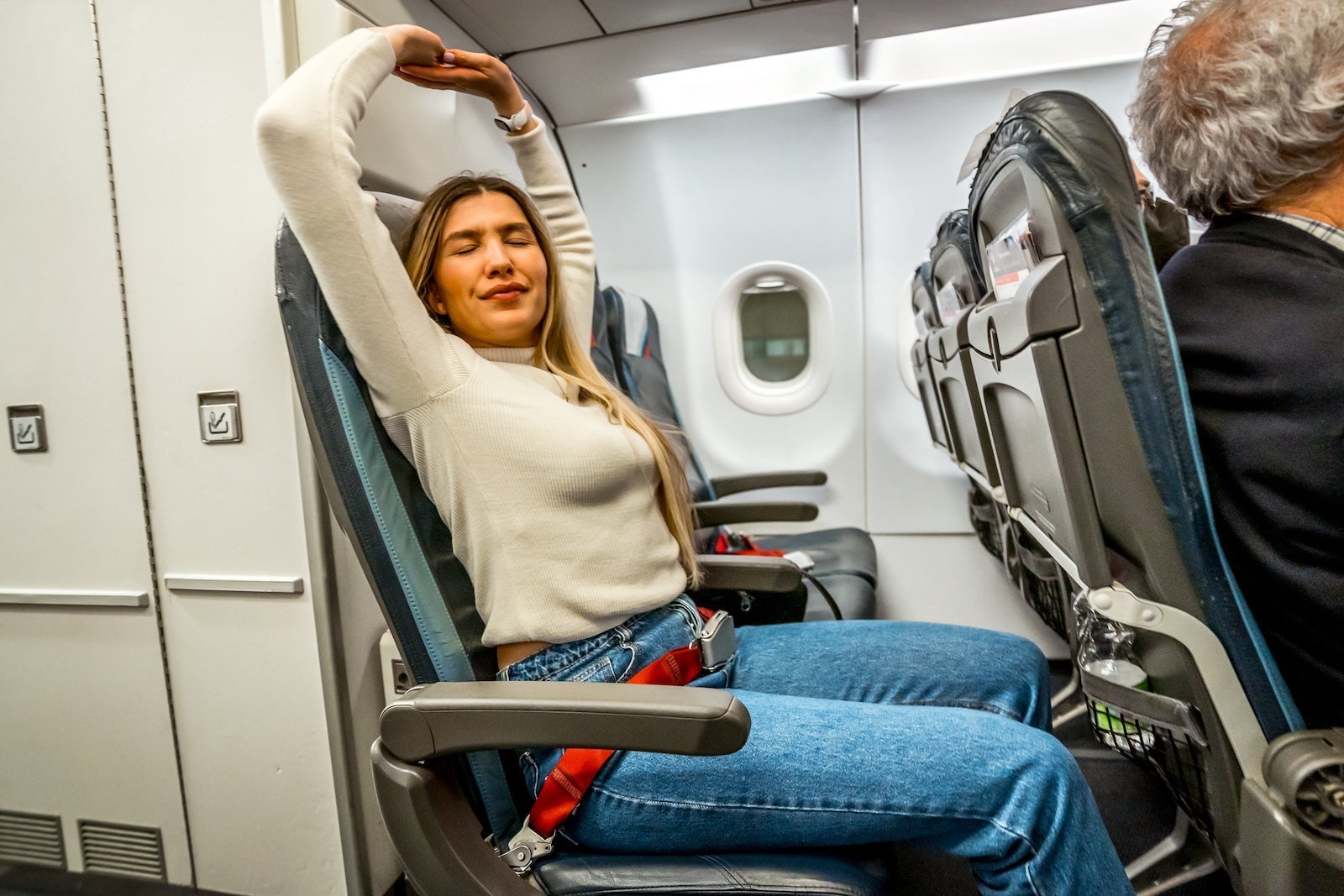 Woman passenger stretching on the airplane