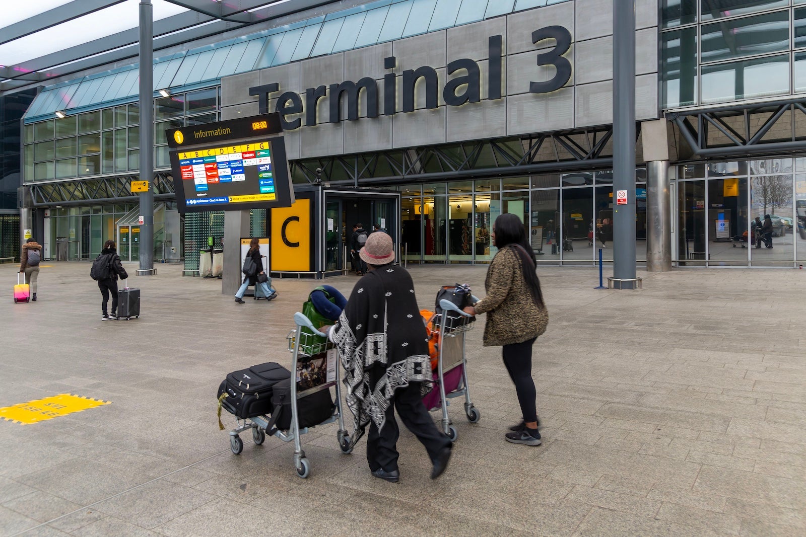 Passengers with luggage outside Terminal 3 building, London Heathrow Airport, England, UK
