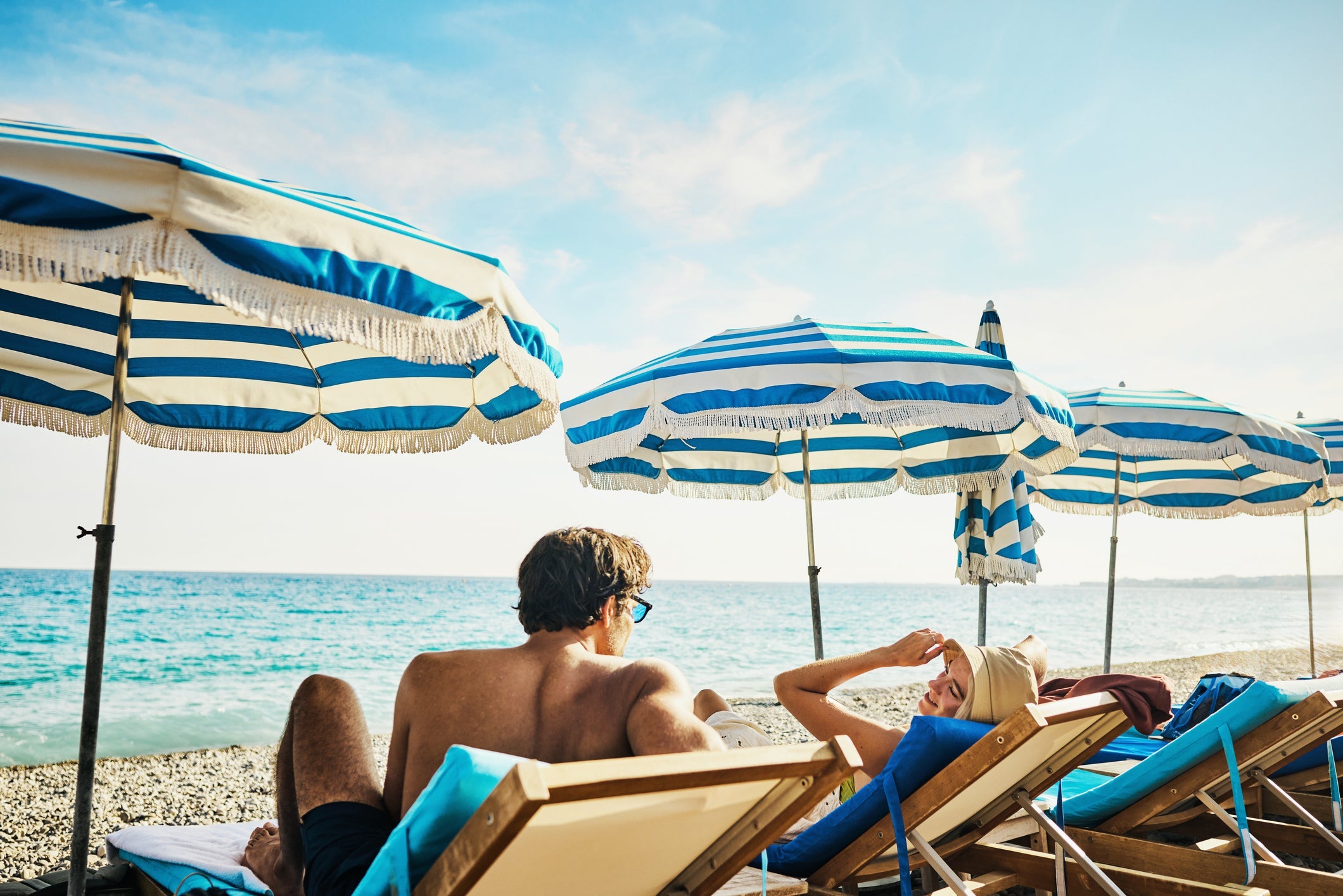 Young adult couple relaxing on the beach on holiday at a luxury hotel on the Côte d'Azur in South France.