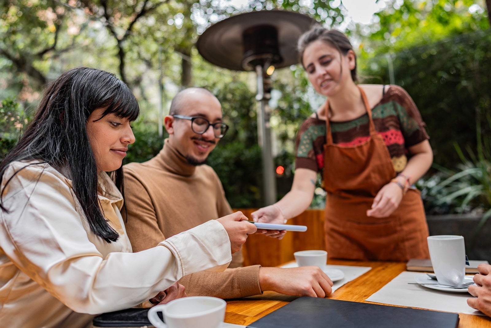Young woman making contactless payment on a coffee shop