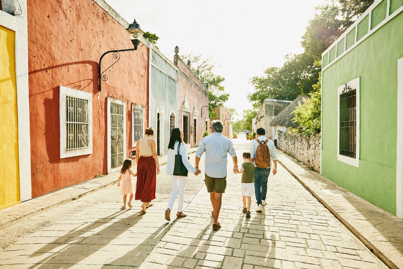 Wide shot rear view of multigenerational family holding hands while exploring town during vacation