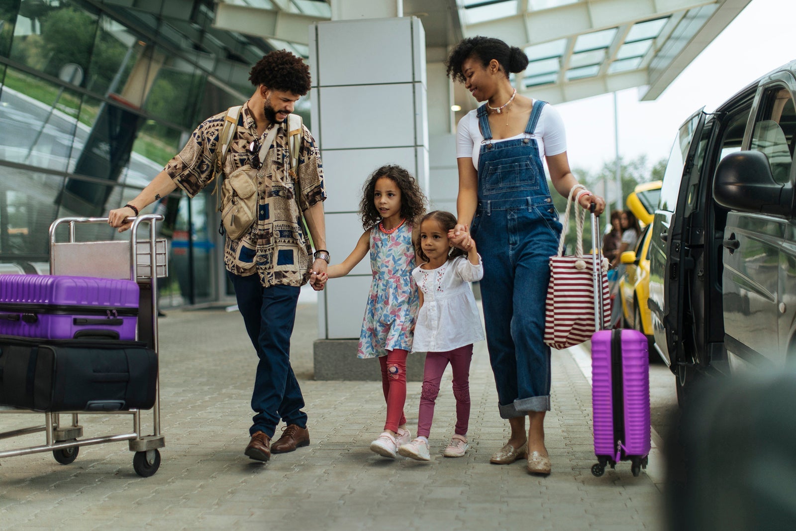 Family-arriving-at-airport-carrying-luggage-at-departure-drop-off_mihailomilovanovic-copy