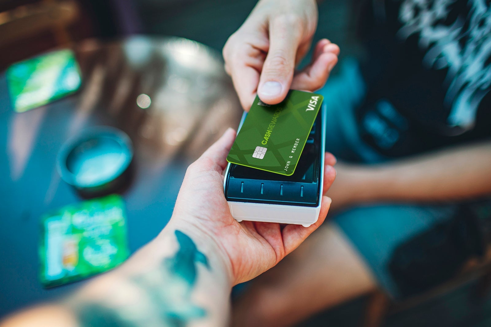 Adult man paying with credit card at cafe, close-up of hands with credit card and credit card reader