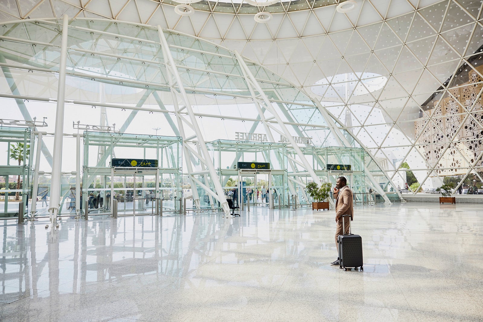 Wide shot businessman taking on phone in airport arrivals after flight