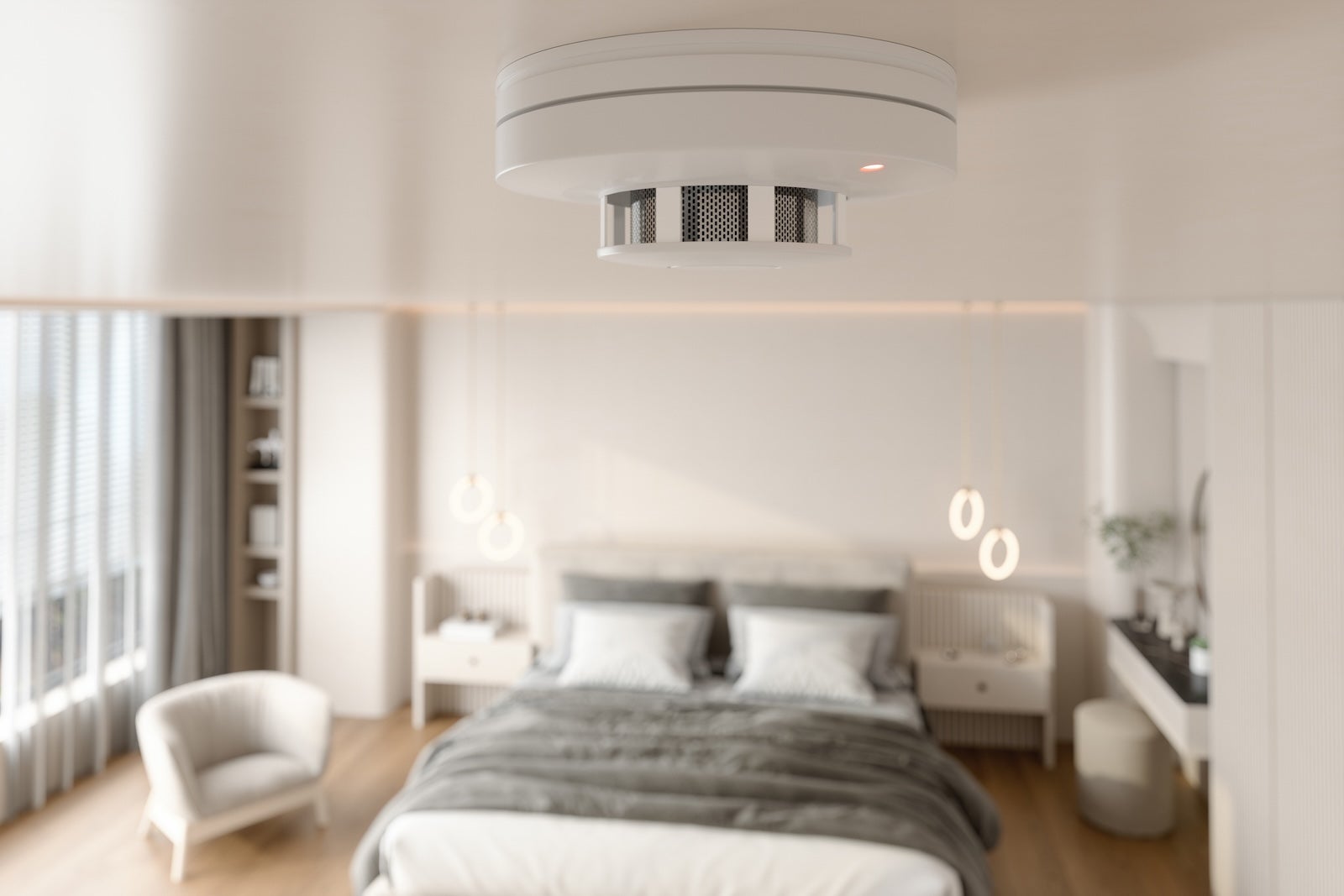Close-up View Of Smoke Detector At Ceiling With Blurred Bedroom Background