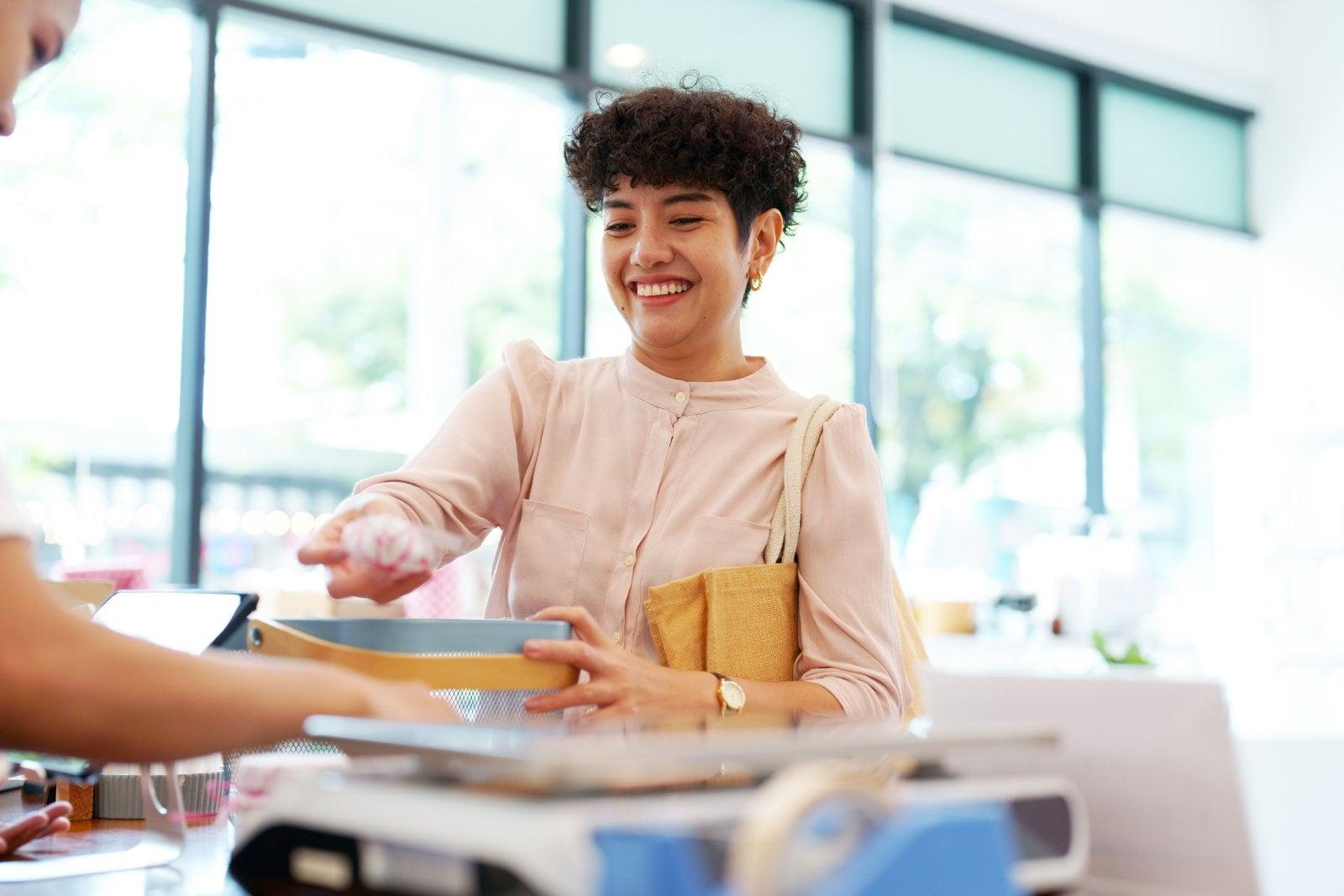 A woman paying for purchase in retail store and bring reusable bags
